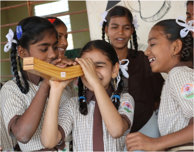 School girls exploring a wooden kaleidoscope